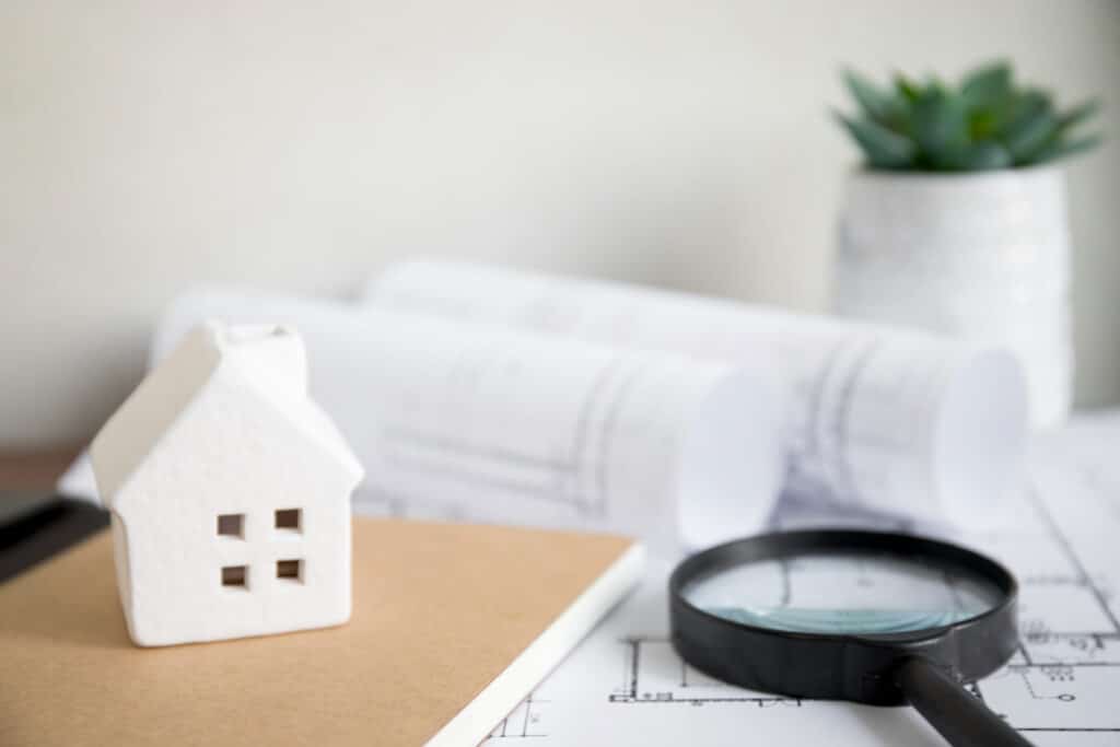 Maison miniature examinée avec une loupe symbolisant l'état des lieux d'un logement à Caen.