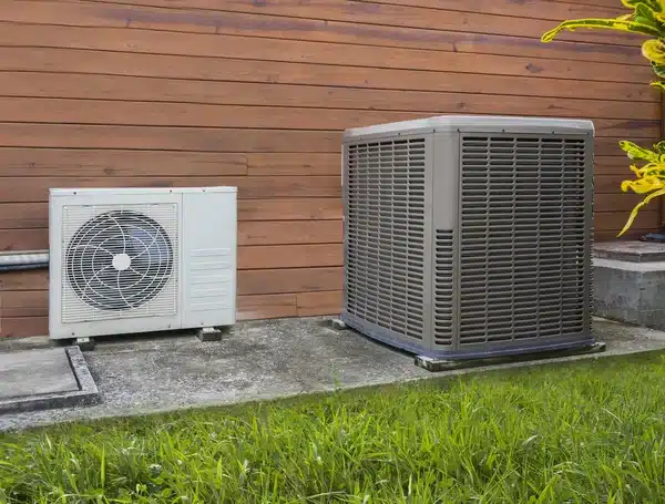 Deux unités extérieures de climatisation sur dalle béton, bardage bois, pelouse en avant-plan à Caen