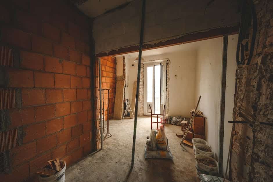 Intérieur en rénovation à Fécamp avec murs en briques, étaiement temporaire, sacs de mortier et matériel de chantier