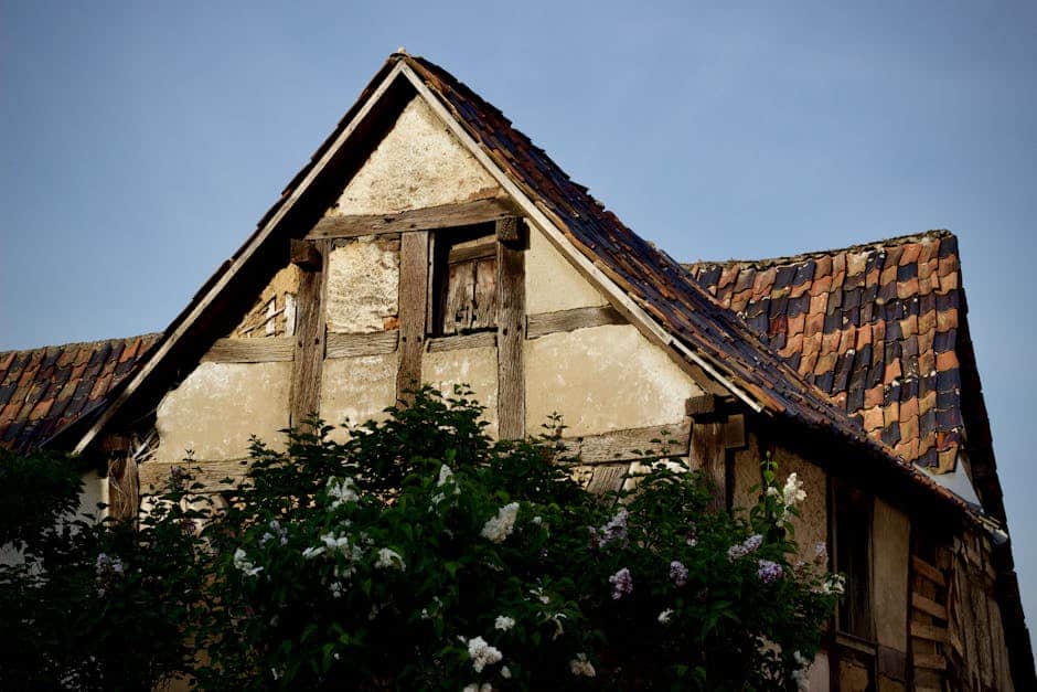 Façade en colombages avec toiture en tuiles anciennes à Mortagne-au-Perche, structure bois apparente, enduit dégradé